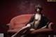 A naked woman sitting on a red couch.