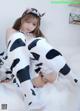 A woman in a cow costume sitting on a bed.