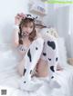 A woman in a cow costume sitting on a bed.