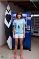 A woman standing in front of a vending machine with a surfboard.