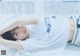 A woman laying on top of a bed wearing a white shirt.