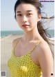 A woman in a yellow tank top standing on a beach.