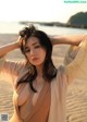 A woman in a beige dress posing on a beach.