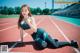 A woman sitting on a running track with her legs crossed.