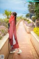 A woman wearing a red scarf standing on a brick walkway.