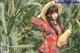 A woman in a red dress and straw hat holding a squash.